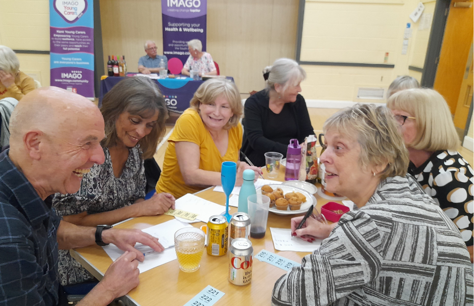 quiz team sat around their table laughing with quiz hosts in the background
